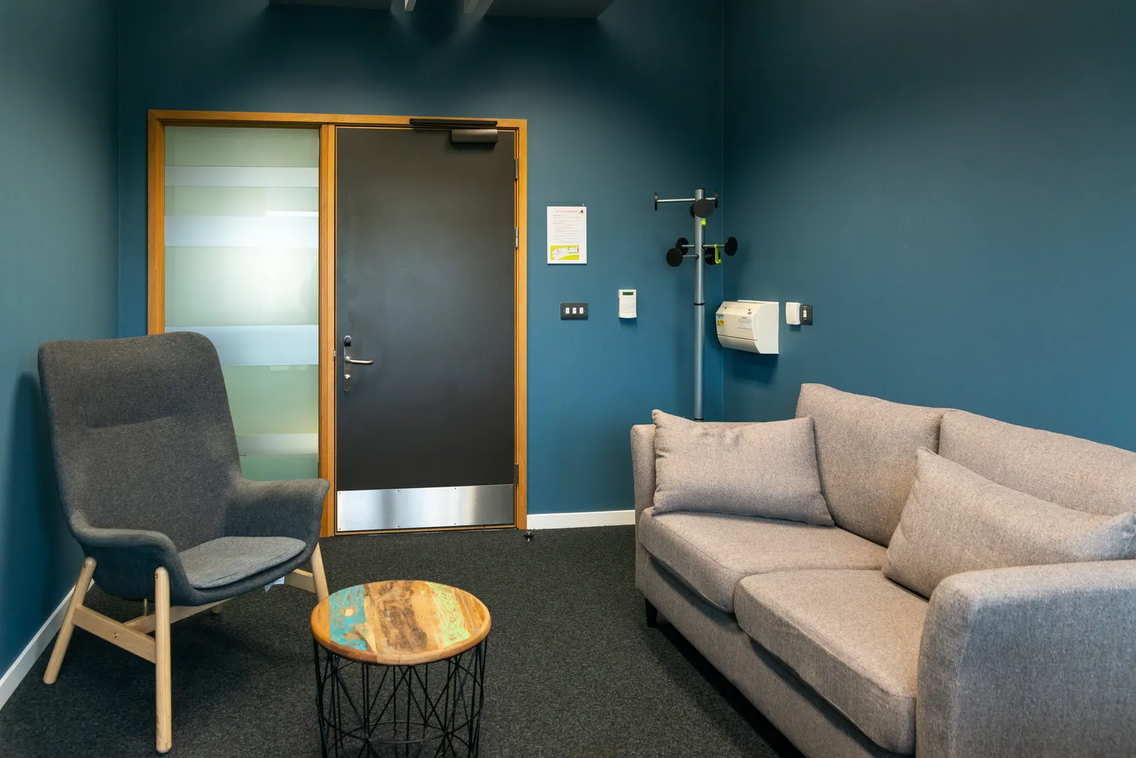 A quiet consulting room with two chairs, a low table and the door closed